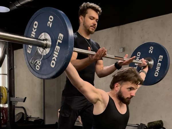 Trener Konrad Grzesik szkoli trenera Karola Domańskiego w sztuce olimpijskiego dwuboju siłowego na siłowni Fabryka Ciao w Krakowie.