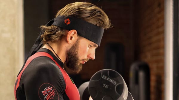 Trener personalny i specjalista biomechaniki, Karol Domański, wyciska hantle Eleiko na biceps.